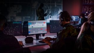 Man is sitting in front of a PC in a military control center