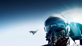 Head of a pilot within a helmet in front of the blue sky with a eurofighter in the background