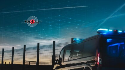 A police van observing a drone flying over a cordoned-off area.