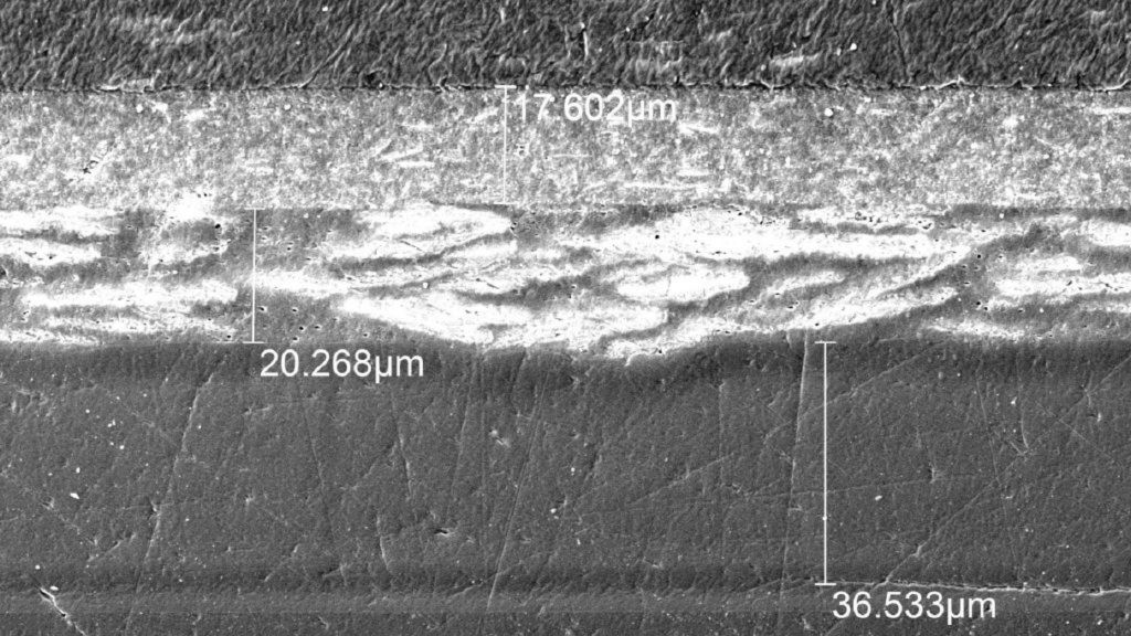 图 1：显示汽车保险杠样本的不同层的显微图像，从上到下依次是基材 (PP)、底漆、色漆和清漆。